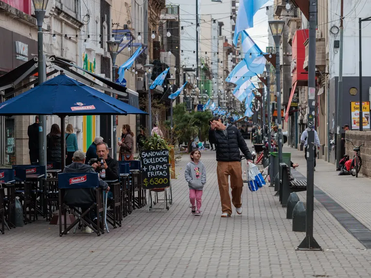 Peatonal San Martín de Santa Fe Capital, con comercios y bares a ambos lados, banderas argentinas y personas caminando por el paseo peatonal.