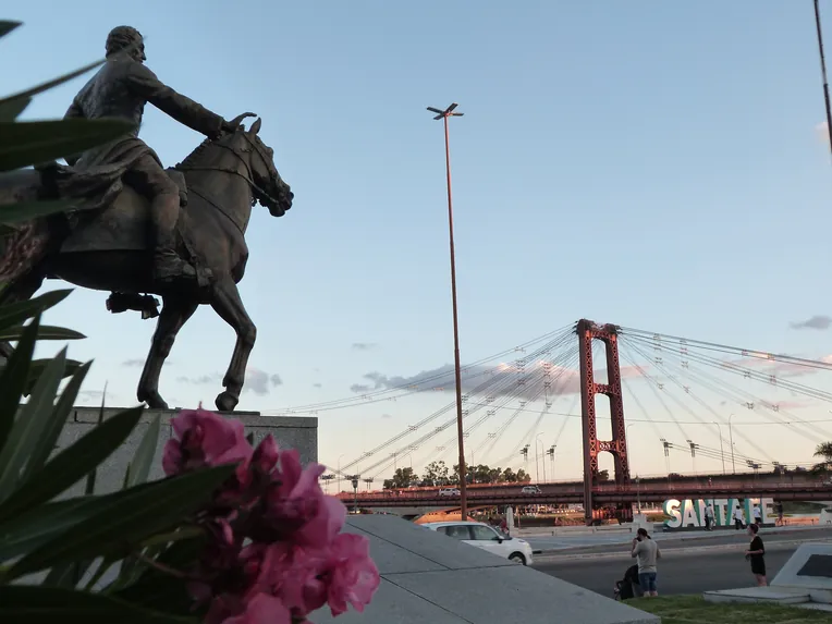 Monumento ecuestre al Brigadier Estanislao López, gobernador de Santa Fe junto al Puente Colgante de Santa Fe, con el río y la ciudad de fondo.