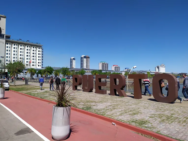 Zona del Puerto de Santa Fe, con el cartel “PUERTO”, la costanera y edificios de la ciudad al fondo.