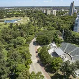 Vista aérea del Anfiteatro Juan de Garay en el Parque del Sur de Santa Fe, destacando sus gradas semicirculares, un escenario techado y un entorno rodeado de árboles y el lago.