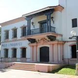 Fachada neocolonial blanca del Museo Etnográfico en Santa Fe, destacando sus letras en la pared, escalinatas de entrada y un balcón de madera oscura.