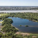 Vista aérea de la Reserva Ecológica de la UNL en Santa Fe, con una gran laguna central rodeada de vegetación autóctona y la ciudad de fondo.